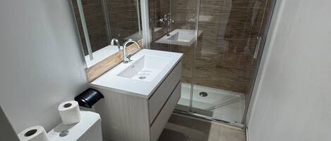 Un baño moderno con inodoro, lavamanos y ducha.