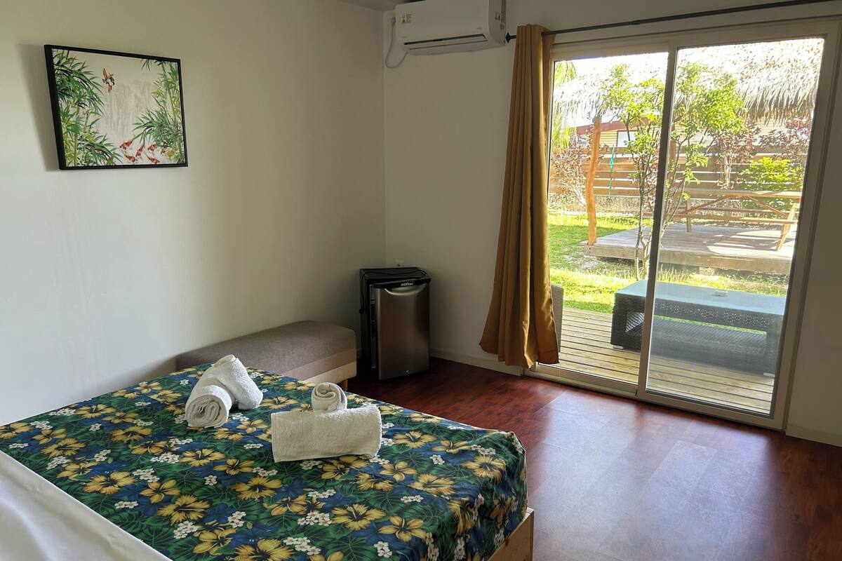 Quarto de hotel com cama, um cesto de lixo pequeno, aparelho de ar condicionado e vista para o exterior.