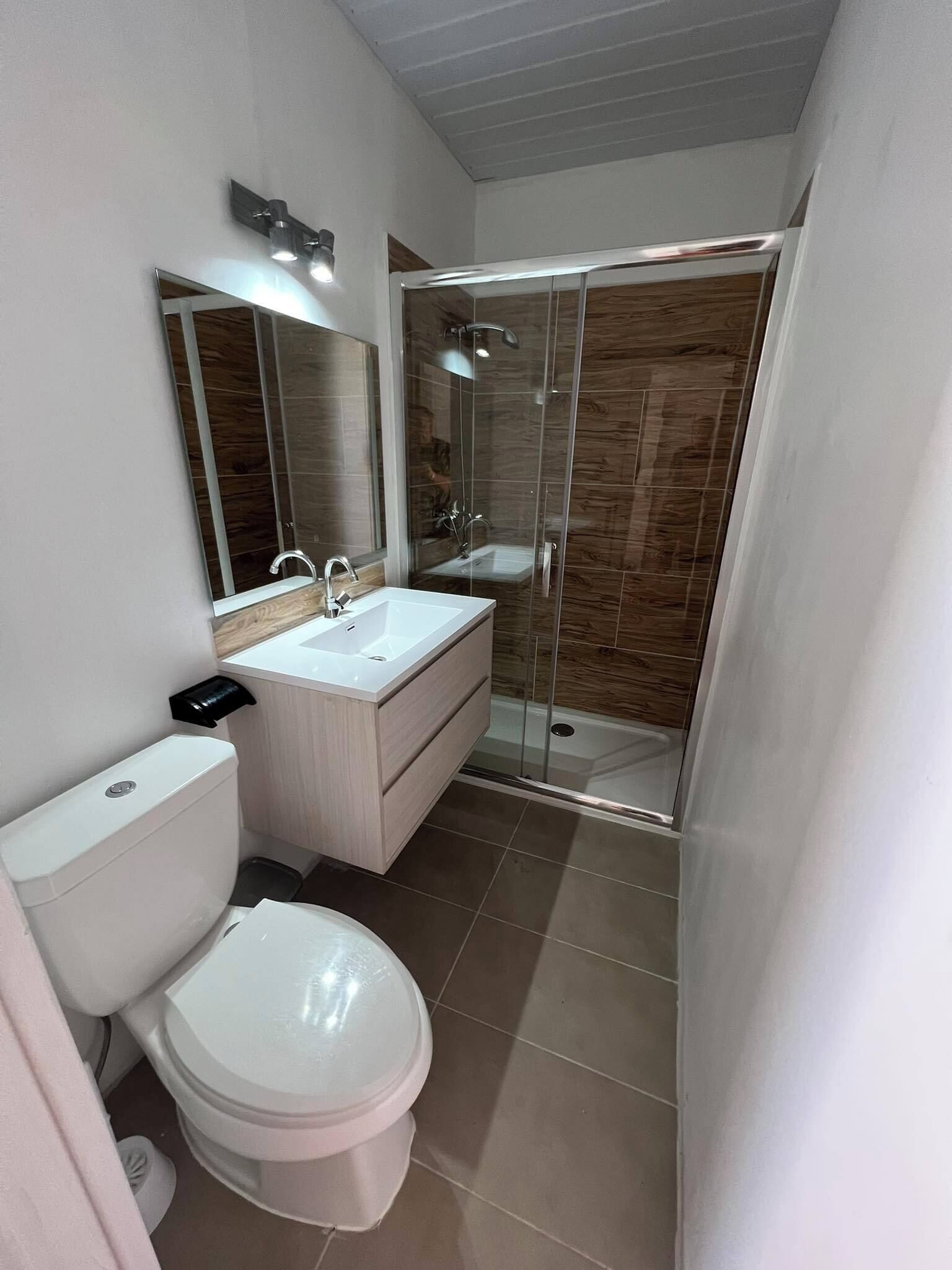 Ein modernes Badezimmer mit Toilette, Waschbecken und einer Duschkabine.