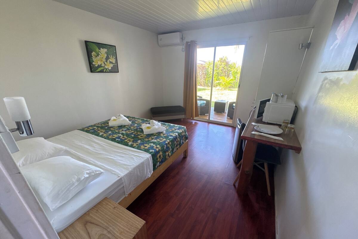 Quarto com duas camas, uma escrivaninha, uma cadeira, uma janela com cortinas e ar condicionado.