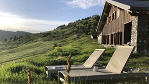 A chalet with a sloped roof, stone walls, and a grassy hillside view. - Superbe Chalet D'alpage Avec vue Spectaculaire - Samoens Morzine col Joux Plane (Verchaix)