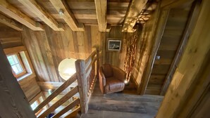 A wooden staircase leading to a loft bedroom with a large window, a wooden chair, and a wall-mounted picture. - Superbe Chalet D'alpage Avec vue Spectaculaire - Samoens Morzine col Joux Plane (Verchaix)