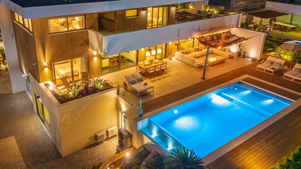 A modern two-story house with a swimming pool, outdoor seating, and a well-lit patio area. - Luxury Beach Villa - Casa do Forte- Infinity pool. (Albufeira)