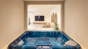 A modern bathroom with a large bathtub, a white sofa, and a flat-screen TV in the background. - Luxury Beach Villa - Casa do Forte- Infinity pool. (Albufeira)