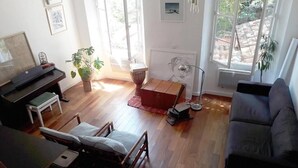 Ein Wohnzimmer mit einer Couch, einem kleinen Tisch, einem Sessel, einem Klavier und einer Heizung.
