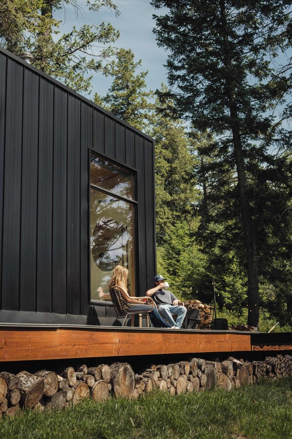 A modern building with a large window, a wooden deck, and a stone wall.