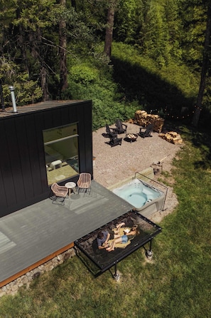 Um terraço moderno ao ar livre com hidromassagem, área de estar e lareira.