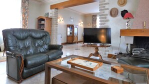 Ein Wohnzimmer mit Ledersofa, Flachbildfernseher, Couchtisch und Kamin.