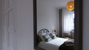 Ein Schlafzimmer mit einem Bett, einem Nachttisch, einem Sessel und einer Pendelleuchte.