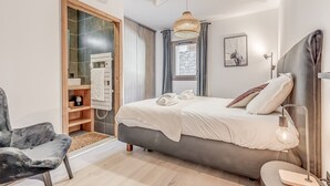 A modern bedroom with a bed, a chair, a wardrobe, and a hanging light fixture.