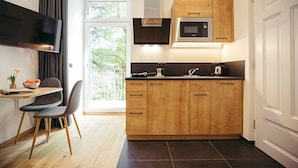 A modern kitchen with wooden cabinets, a built-in microwave, and a dining area with a chair and table.
