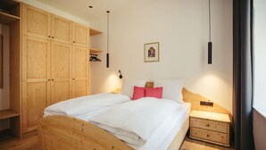 Un letto di legno con biancheria bianca, un comodino, un armadio in legno e un quadro appeso al muro.