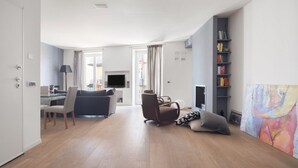 A modern living room with a sofa, armchair, and a flat-screen TV.