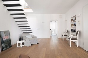 Un salon moderne avec un escalier, un canapé et un coin repas avec des chaises.