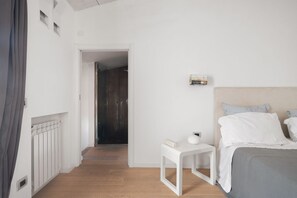 A bedroom with a bed, bedside table, and a small shelf with books. - La Cala Terrace by Domusicily (Palermo)