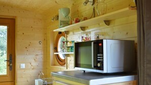 Cocina pequeña con microondas, lavamanos y ventana.