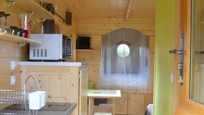 Un interior de madera con una zona de cocina, una mesa de comedor y un ventanal con vistas.