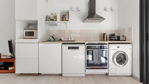 Cozinha compacta com eletrodomésticos embutidos, incluindo lava-louças, forno e micro-ondas.