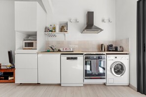 Une cuisine compacte dotée d’appareils électroménagers intégrés, notamment un lave-vaisselle, un four et un four à micro-ondes.