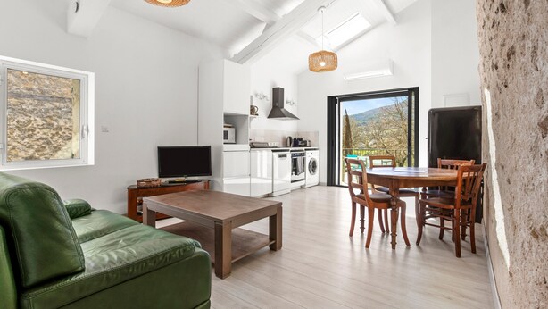 Uma cozinha moderna com eletrodomésticos brancos, uma área de refeições com mobiliário de madeira e uma janela grande com vista.