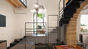 Una cocina moderna con encimera negra, una mesa de comedor de madera y vistas a una pared de piedra y una ventana.