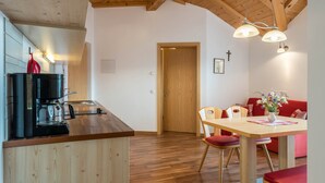 Een keuken met een koffiezetapparaat, houten plafond en een eethoek met een tafel en stoelen.