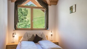 A double bed with checkered bedding, two bedside lamps, a window with curtains, and a small picture on the wall. - Apartment 'Solerhof Terrace' with Mountain View, Private Terrace and Wi-Fi (Laion)