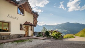 A building named 'Solerhof' with a wooden facade, a bench outside, and a view of mountains. - Apartment 'Solerhof Terrace' with Mountain View, Private Terrace and Wi-Fi (Laion)