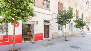 A building with a red and white facade, a door, and a small tree in front.