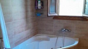 Une salle de bain avec une baignoire sur pieds, une fenêtre et une étagère contenant des articles de toilette.