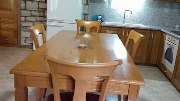 Ein Holztisch mit Stühlen, eine Steinwand, ein Kühlschrank und Holzschränke in einer Küche.