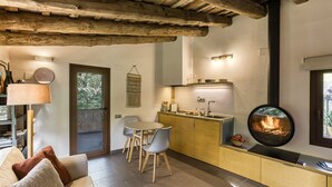 A cozy kitchen with a central island, wooden beams, and a fireplace.