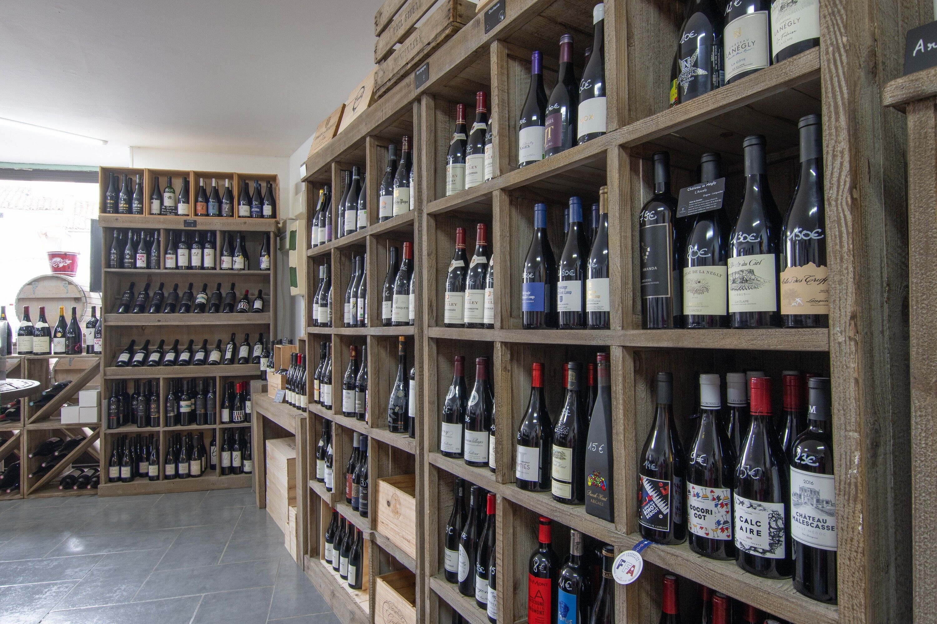 A wine shop with wooden shelves stocked with various wine bottles.