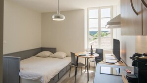 Een knus verblijf met een bed, een eettafel, stoelen, een kleine televisie en een raam met uitzicht.