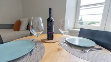 A dining table with a bottle of wine, glasses, plates, and cutlery.