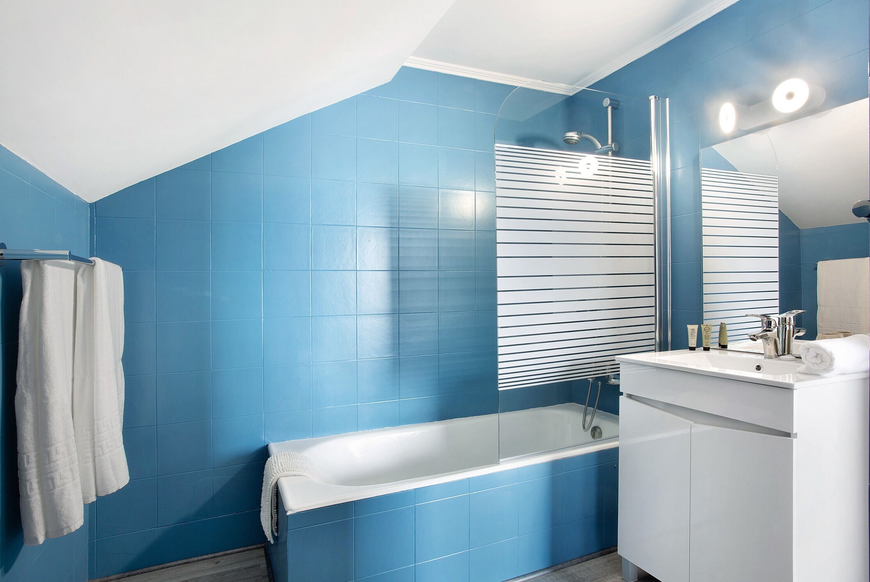 Ein Badezimmer mit blauen Wänden, einer weißen Badewanne, einem weißen Waschbecken und einem Spiegel.