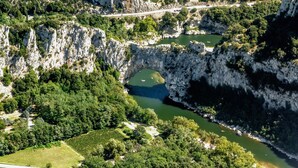A mountainous landscape with a river, a bridge, and a vineyard. - Apartment In A Hotel 'Chatus' with Wi-Fi and Air Conditioning (Ruoms)