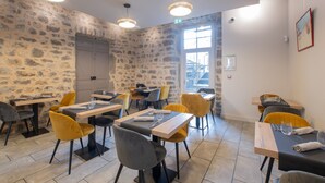 A restaurant with stone walls, yellow and grey chairs, and wooden tables. - Apartment In A Hotel 'Chatus' with Wi-Fi and Air Conditioning (Ruoms)