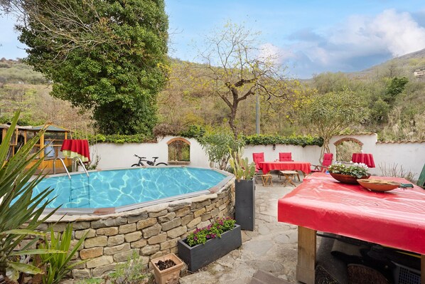 Una piscina rodeada de muros de piedra, muebles de exterior y plantas en macetas.