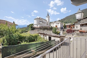 Un village européen traditionnel, avec une église, des bâtiments en pierre et un ciel dégagé.