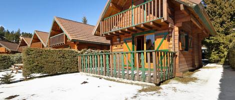 A wooden cabin with a balcony, surrounded by snow.
