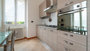Une cuisine moderne équipée d’une cuisinière à gaz, d’un four et d’un four à micro-ondes. On y trouve également un coin repas avec une table et des chaises en verre.