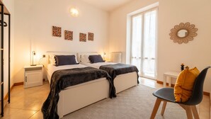 Une chambre moderne avec deux lits, un petit bureau et une chaise. On y trouve également des éléments décoratifs sur les murs et un miroir.