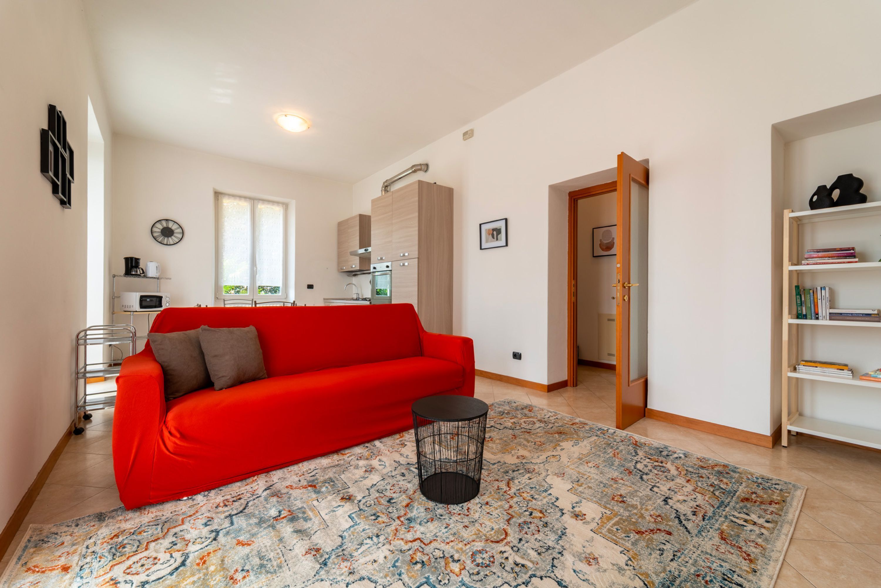 A modern living room with a red sofa, a small round table, and a patterned rug.