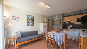 Una cocina compacta con una mesa de comedor, un sofá y un refrigerador.