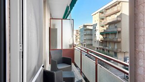 Un balcon agrémenté de meubles en osier, avec vue sur les immeubles voisins et un ciel dégagé.