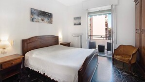 Une chambre à coucher avec un lit, une table de chevet, une lampe, des œuvres d’art et une vue sur l’extérieur.
