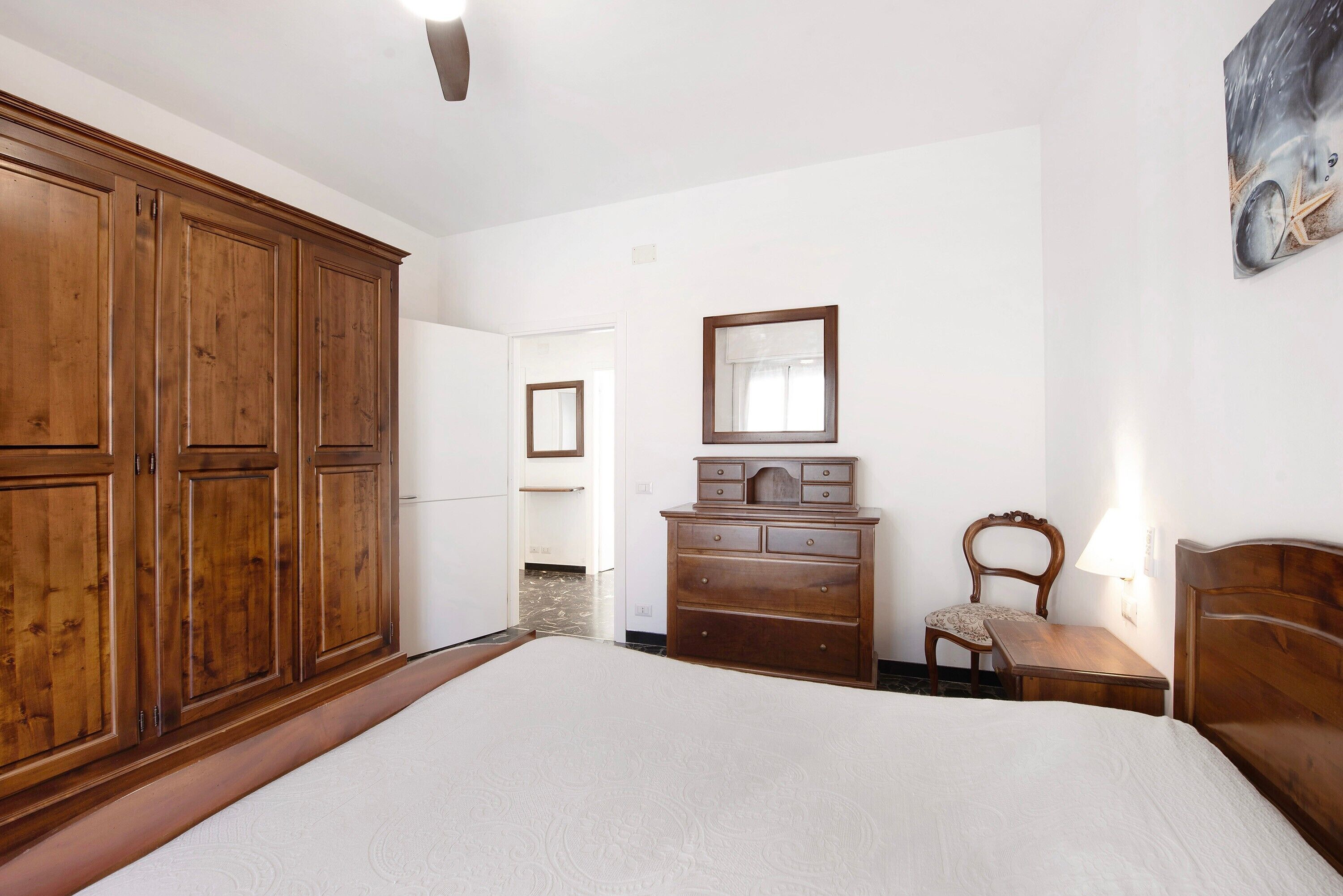 Une chambre avec une grande armoire en bois, une commode, une chaise et un lit.