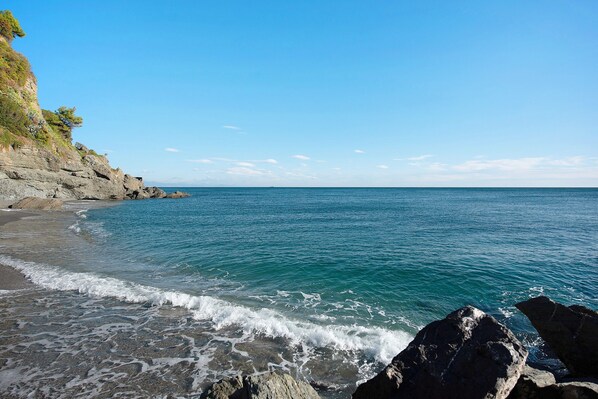 A coastal beach with rocky terrain and clear blue waters.
