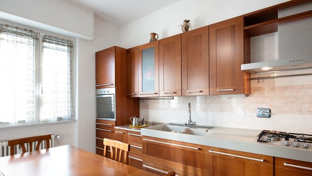 A modern kitchen with wooden cabinets, a stainless steel sink, and a gas stove. - Apartment 'Le Vele' with Sea View, Shared Garden and Balcony (Albissola Marina)